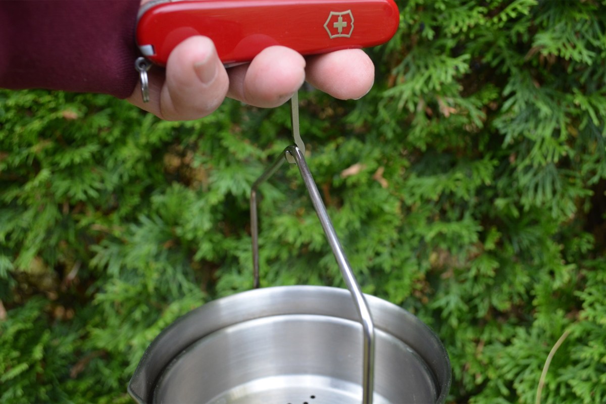 The Huntsman’s multipurpose hook being used to lift a pot by its bail