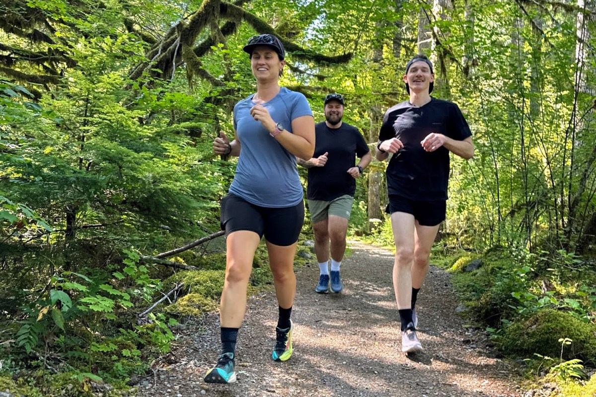 Three runners moving along a wooded trail with SpeedArc Peak shoes in front