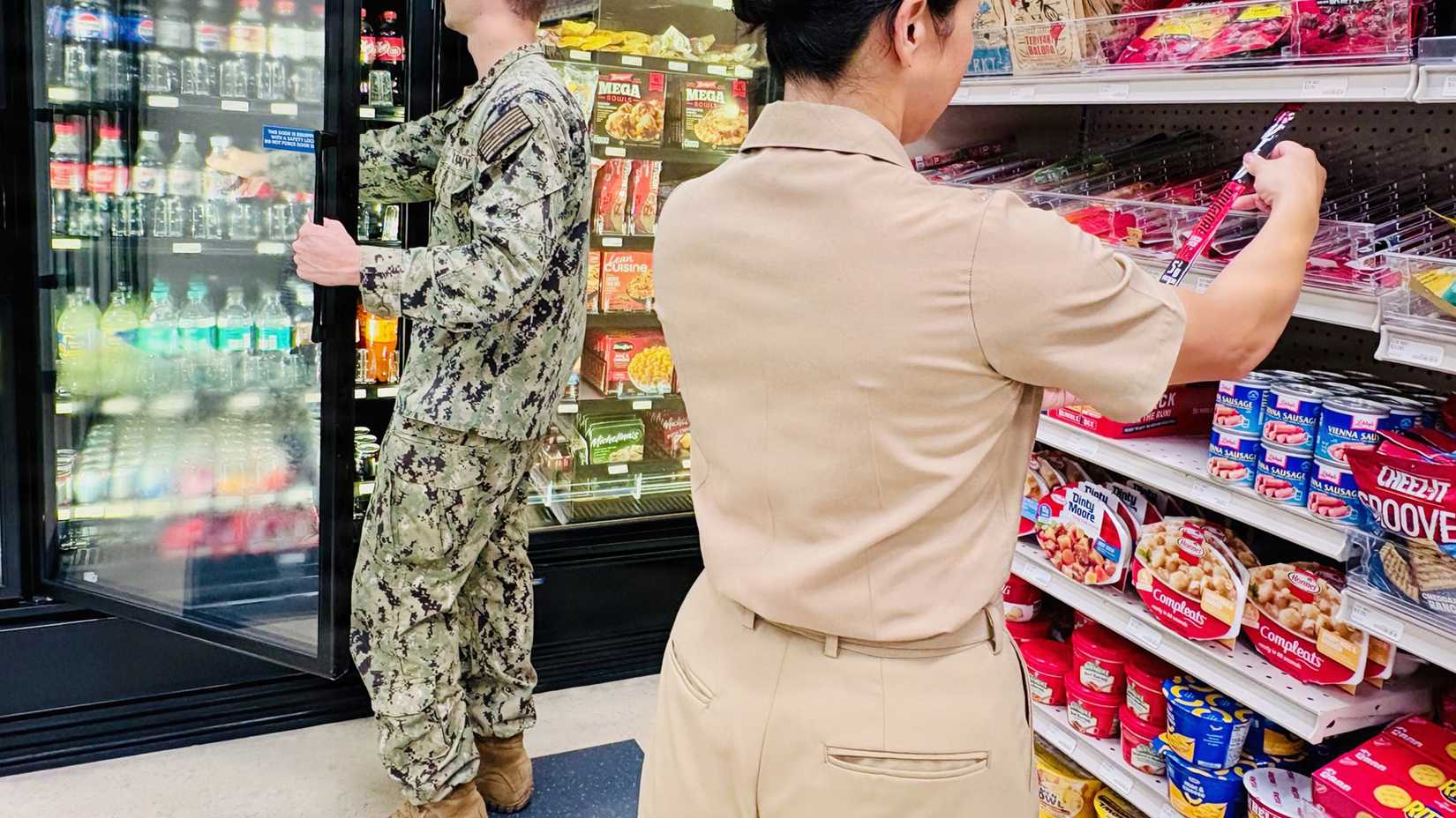 A female sailor wearing redesigned Service Khaki slacks with back pockets shops alongside another sailor at a Navy Exchange.