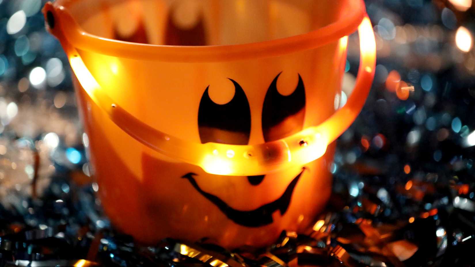 An orange jack-o'-lantern candy bucket glows among Halloween decorations at a military Trunk-or-Treat event.